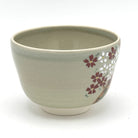 Side view of the hand-painted Kyo-yaki Sakurazume chawan showing clusters of pink and white cherry blossoms against the soft beige glaze