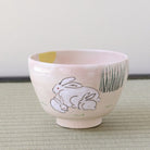 Kyo-yaki Tsukimi matcha bowl featuring a parent and child rabbit beneath a full moon with green grass details on a soft pink glaze