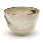Angled view of the Kyo-yaki yuzu chawan showing its rounded profile, ivory glaze, and partial hand-painted yuzu and green leaf decoration