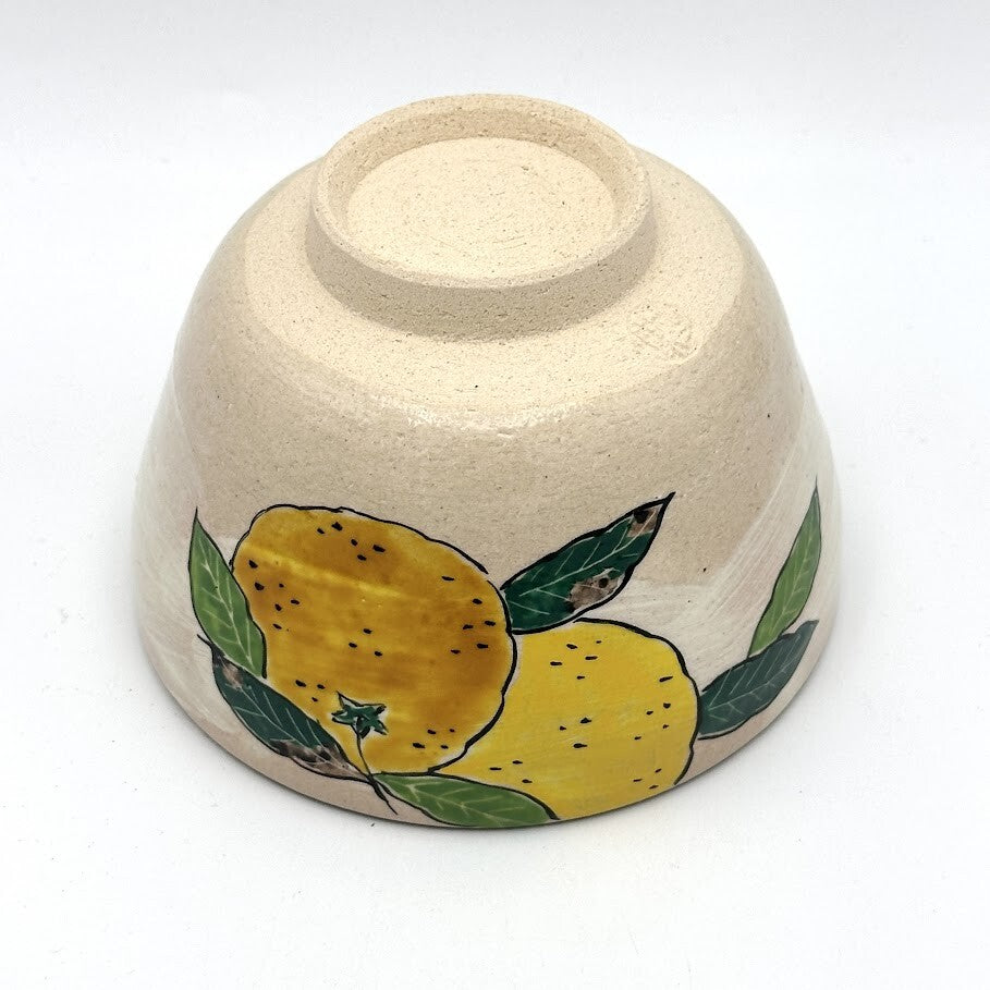 Underside view of the Kyo-yaki yuzu matcha bowl showing its ceramic foot and hand-painted yellow yuzu fruit with green leaf decoration