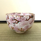 Decorative glass bowl with cherry blossom design on a woven mat