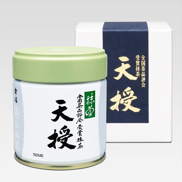 TENJU Ceremonial Grade Matcha of marukyu koyamen in a small green canister with a white label, alongside its packaging box which has Japanese characters and branding.