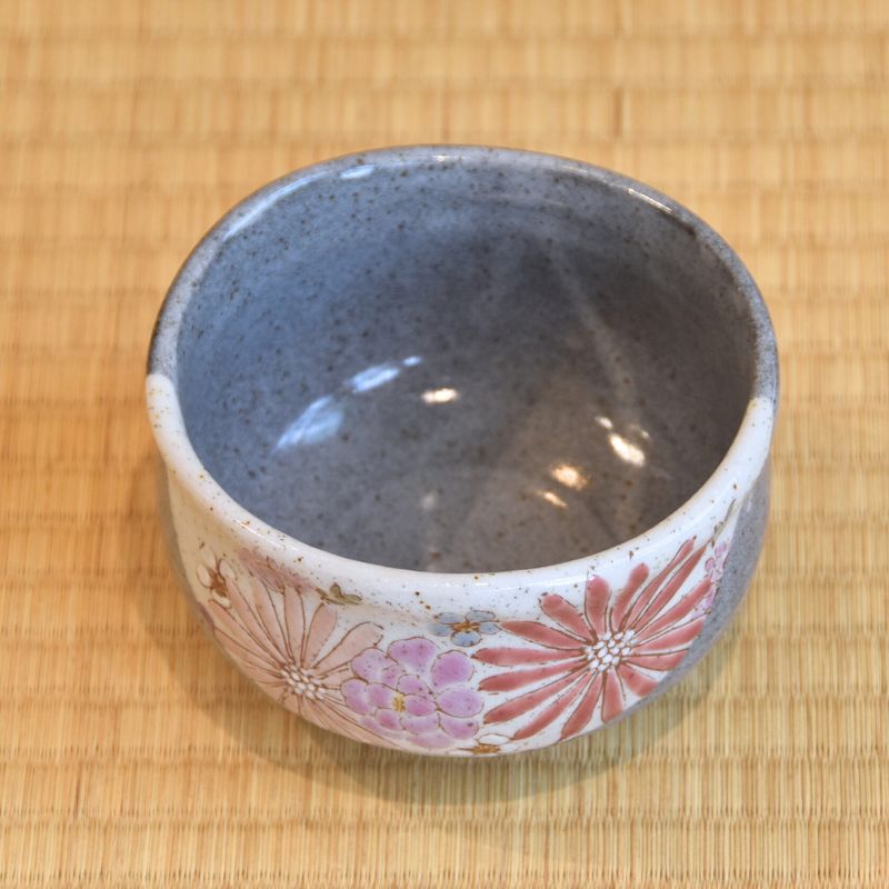 Ceramic cup with floral design on a bamboo mat