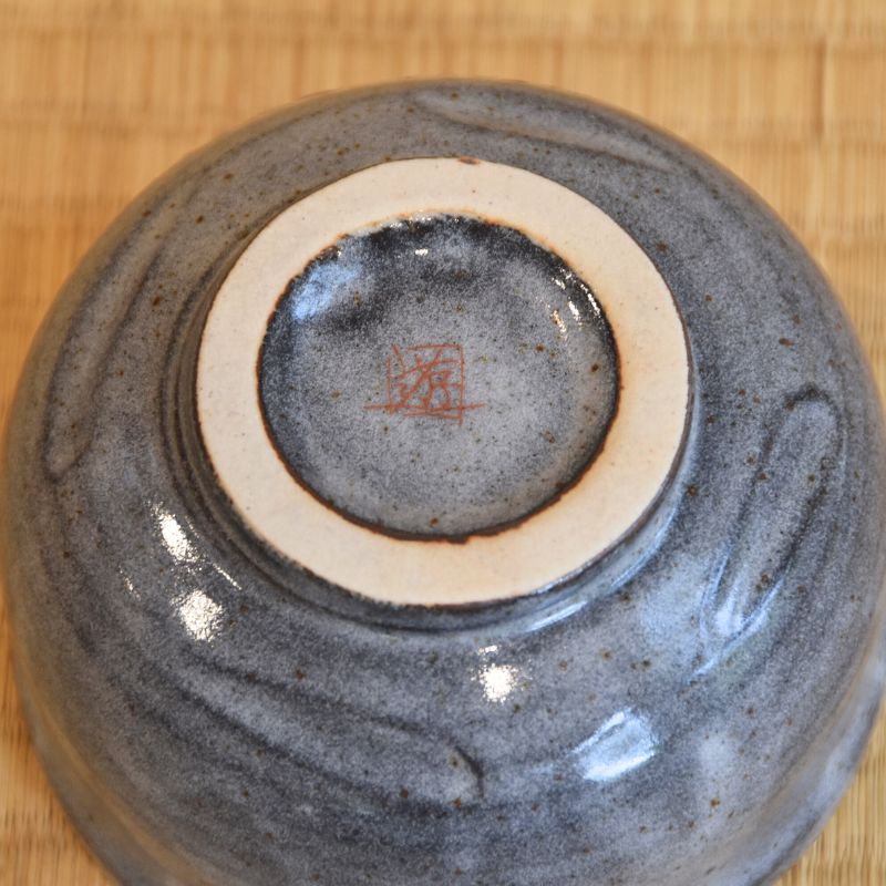 Close-up of a ceramic bowl with a signature on a wooden surface