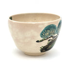 Side view of the Kyo Ware matcha bowl highlighting the hand-painted green pine tree motif against the warm beige glaze