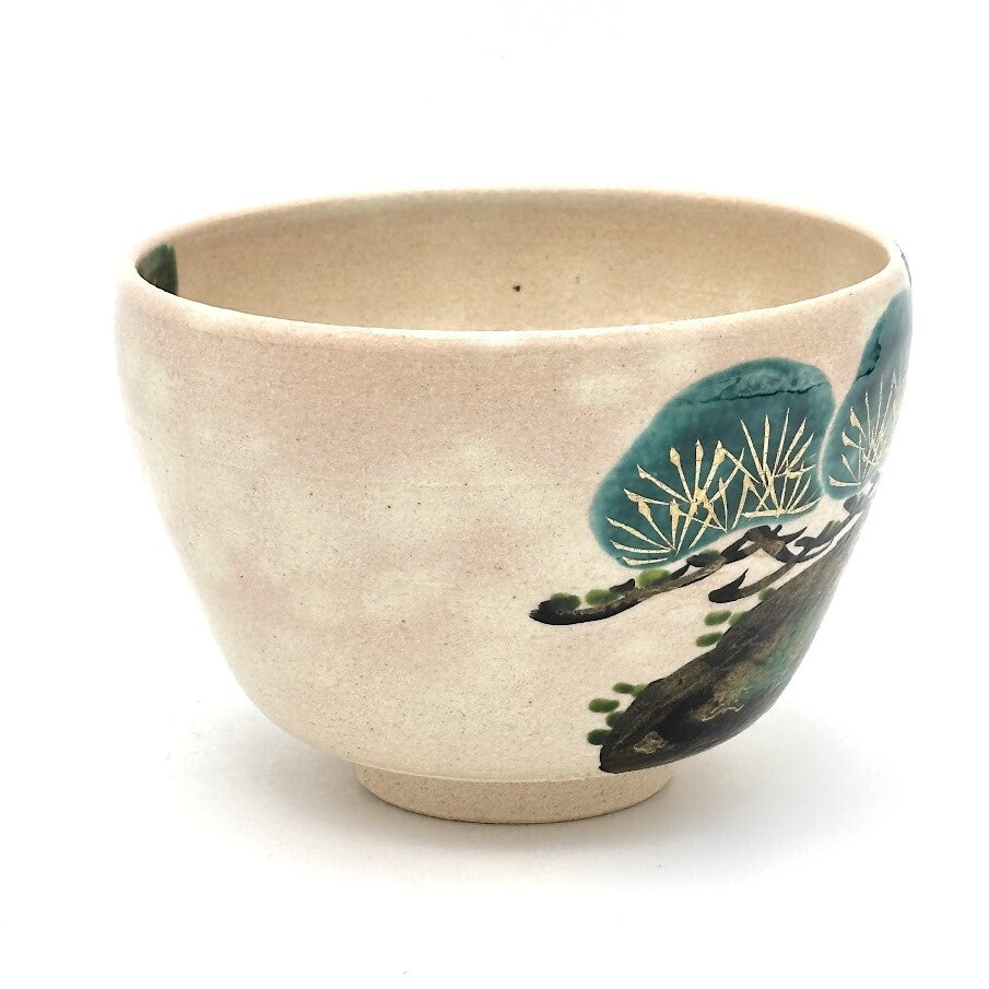 Side view of the Kyo Ware matcha bowl highlighting the hand-painted green pine tree motif against the warm beige glaze