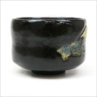 Opposite side of the Black Raku matcha bowl showing blue-green numeral marks and small gold-toned accents on the glossy surface.