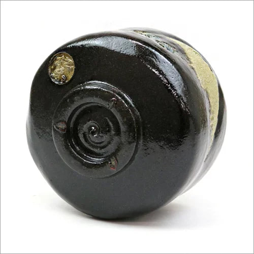 Angled underside view of the Matsuraku Kiln Black Raku matcha bowl showing its circular foot and hand-formed black-glazed base.
