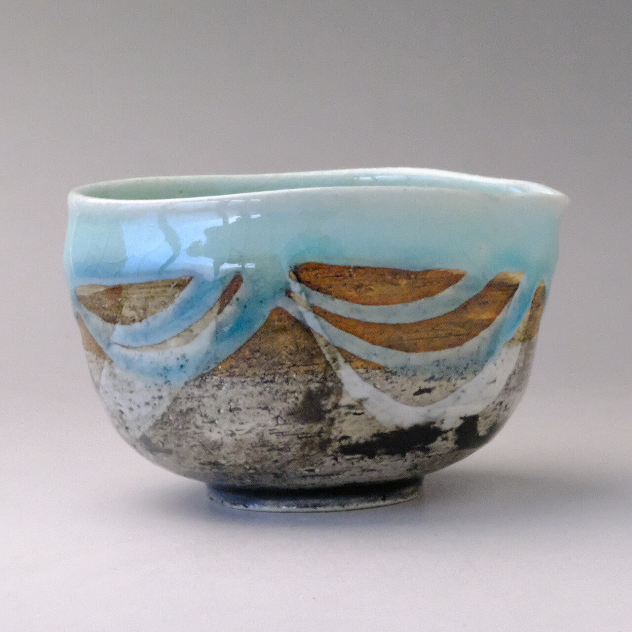 Front view of the matcha pouring bowl showing its softly curved body, glossy mint blue rim, and layered exterior glaze.