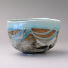 Front view of the matcha pouring bowl showing its softly curved body, glossy mint blue rim, and layered exterior glaze.