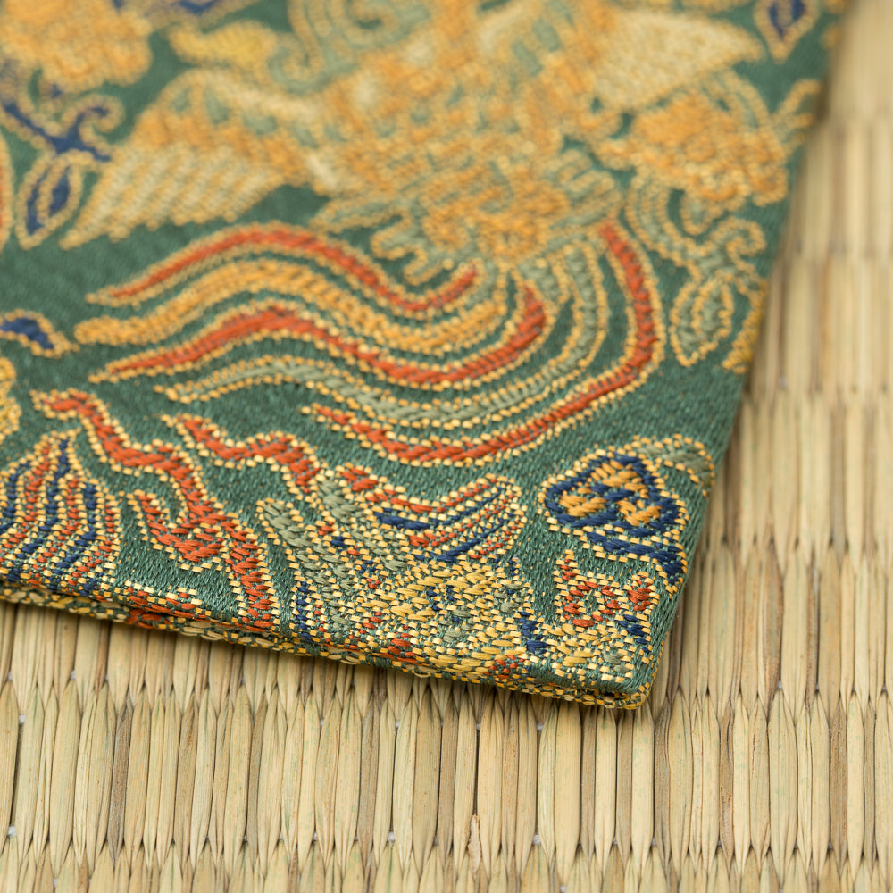 Folded corner of the kobukusa showing its hand-sewn edge, moegi-green ground, clouds, and gold brocade details.