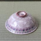 Angled underside view of the Morisato Touraku Hira Chawan showing pale purple floral decoration and raised foot