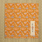 Nashi-ji Kiku Karakusa Nishijin silk dashibukusa displayed on tatami with its Japanese paper title label.