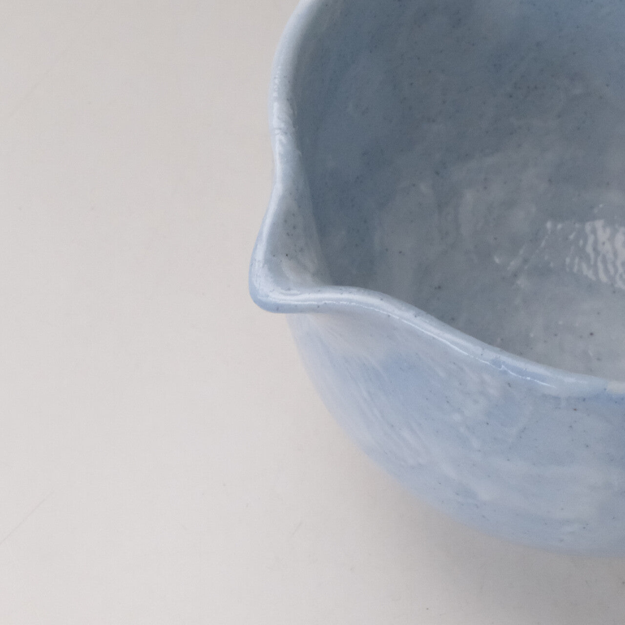 Close-up of the pouring spout and rim of the pale blue katakuchi matcha bowl with a gently mottled glaze.
