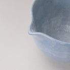 Close-up of the pouring spout and rim of the pale blue katakuchi matcha bowl with a gently mottled glaze.