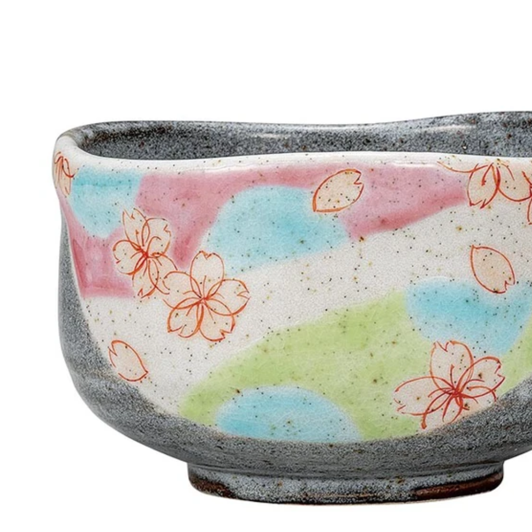 Right angled view of the hand-painted sakura matcha bowl showing cherry blossoms and pastel pink, blue, and green decoration wrapping around the exterior.