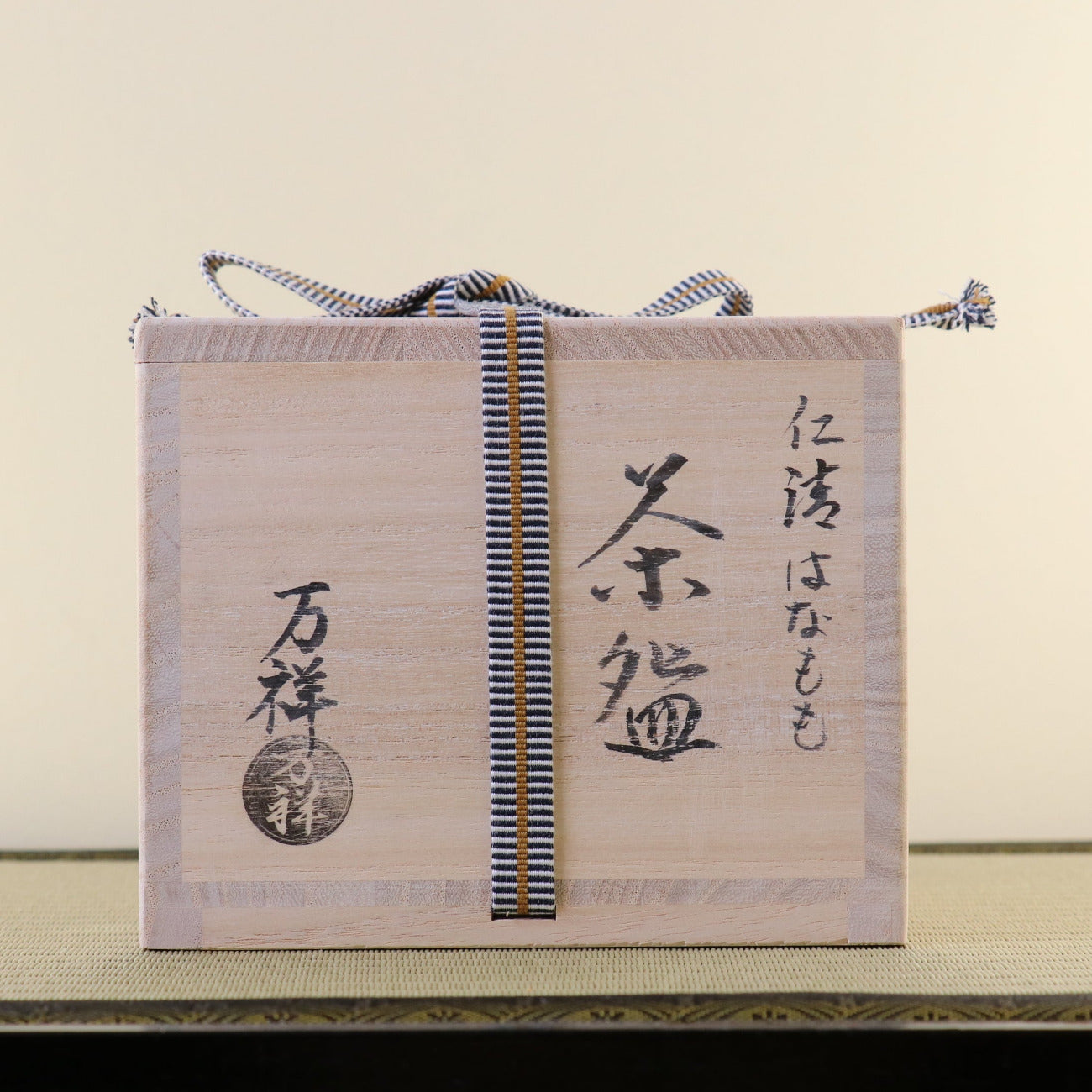 Traditional wooden kiribako storage box for the peach blossom matcha bowl, tied with a cord and inscribed in Japanese calligraphy.