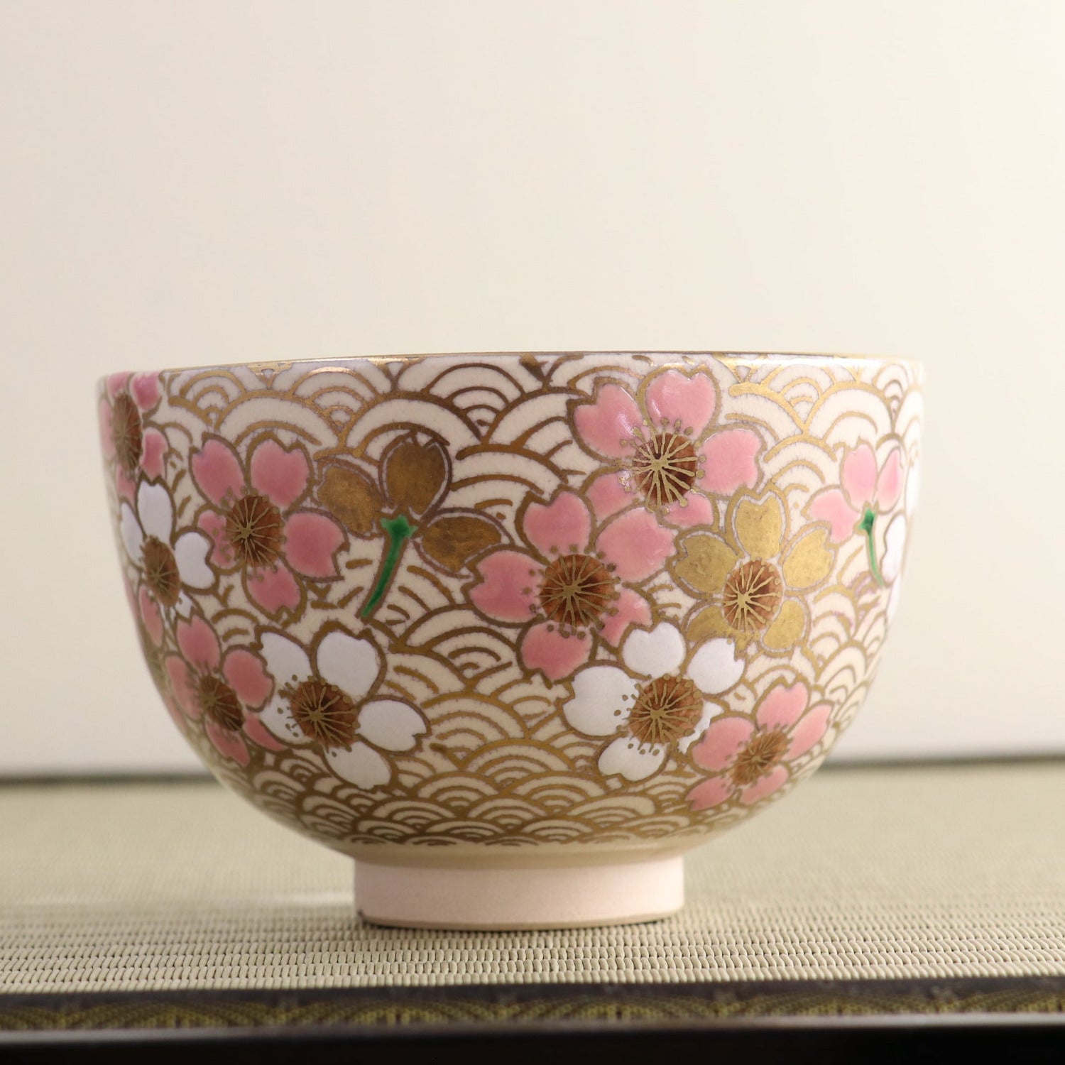 Side profile of the peach blossom matcha bowl showing its rounded form, raised foot, and densely hand-painted floral decoration.