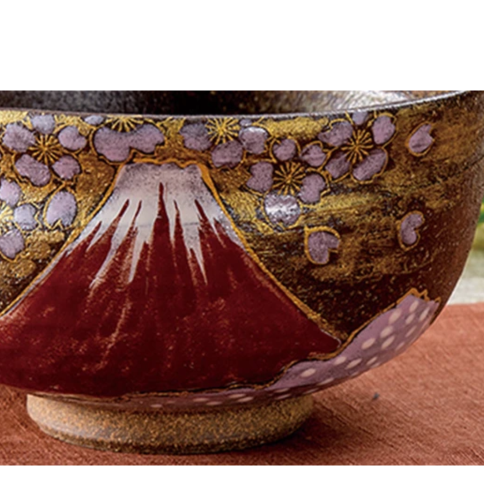 Close-up of the matcha bowl showing the snowcapped crimson Mount Fuji, lavender sakura blossoms, gold-leaf background, and raised foot.