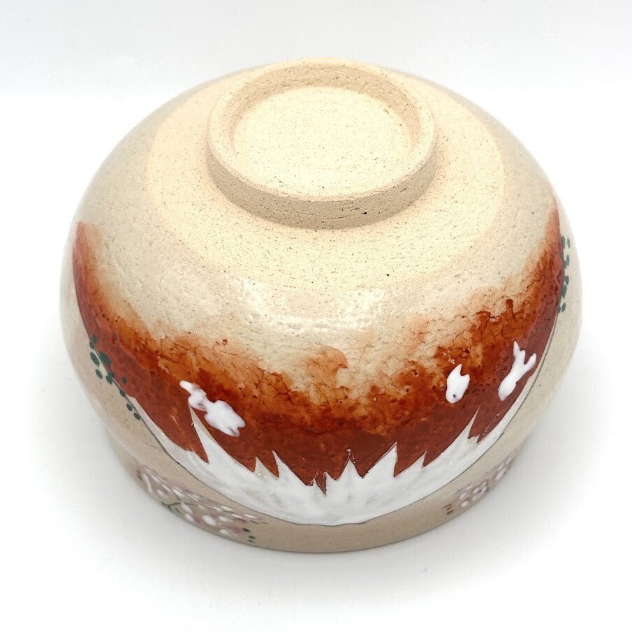 Underside view of the hand-painted matcha bowl showing the foot ring and the Red Fuji design extending around the base.