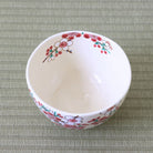 Top view of the red and white plum blossom matcha bowl showing its white interior and flowering branches continuing around the rim.