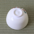 Underside view of the Kyo Ware matcha bowl showing the raised foot ring and red and white plum blossoms along the upper exterior.