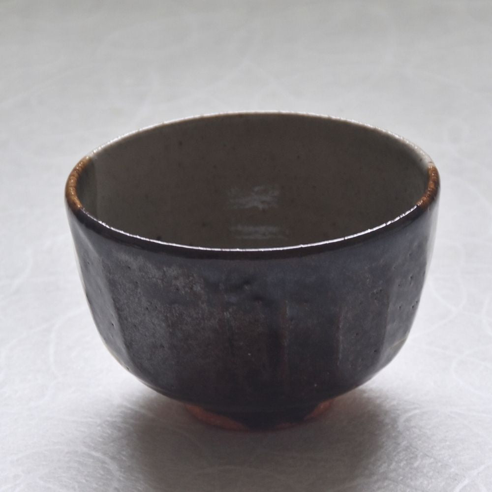 Reverse view of the Ryoji Nakamura matcha bowl showing its deep charcoal-brown glaze and softly rounded form.