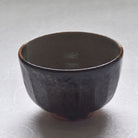 Reverse view of the Ryoji Nakamura matcha bowl showing its deep charcoal-brown glaze and softly rounded form.