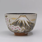 Front view of a hand-painted Kyo Ware matcha bowl by Ryoji Nakamura featuring snowcapped Mt. Fuji, cherry blossoms, and gold-toned clouds.