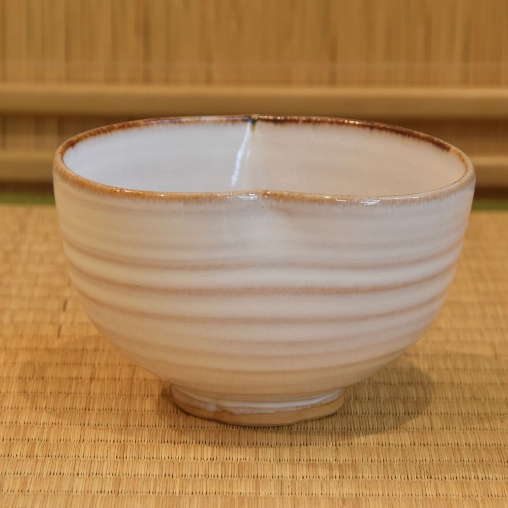 Back view of the Kyo Ware katakuchi matcha bowl showing its softly ridged ivory glaze, warm brown rim, and raised foot.
