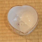 Top view of the petal-shaped katakuchi matcha bowl showing its ivory interior, pointed pouring lip, and a single painted peach petal.