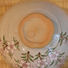 Close-up of the peach-blossom-shaped foot and impressed maker's mark on the underside of the Kyo Ware matcha bowl.