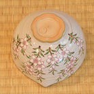 Underside view of the peach blossom matcha bowl showing its floral decoration, pointed form, and peach-blossom-shaped foot.