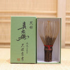 Ryosai Kubo handcrafted Takayama chasen made from Japanese black bamboo with Dark Red #4 thread, displayed beside its presentation box