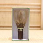 Ryosai Kubo black bamboo Takayama chasen with Lemon #17 thread displayed upright inside its green presentation box