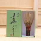 Ryosai Kubo handcrafted Takayama chasen made from Japanese black bamboo with Maroon #5 thread, displayed beside its presentation box