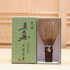Ryosai Kubo handcrafted Takayama chasen made from Japanese black bamboo with Pale Blue #27 thread, displayed beside its presentation box