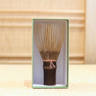 Ryosai Kubo black bamboo Takayama chasen with Coral #3 thread displayed upright inside its green presentation box
