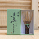 Ryosai Kubo handcrafted Takayama chasen made from Japanese black bamboo with Yellow Green #24 thread, displayed beside its presentation box