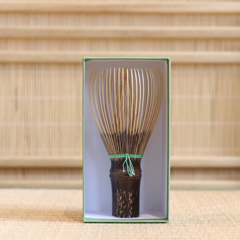 Ryosai Kubo black bamboo Takayama chasen with Yellow Green #24 thread displayed upright inside its green presentation box