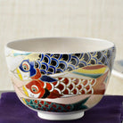 Close front view of the Saiei matcha bowl showing overlapping cobalt blue, red, and turquoise koinobori with detailed scales and gold accents.