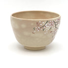 Side view of the Kyo Ware chawan highlighting hand-painted pink and white cherry blossoms on the softly textured beige glaze