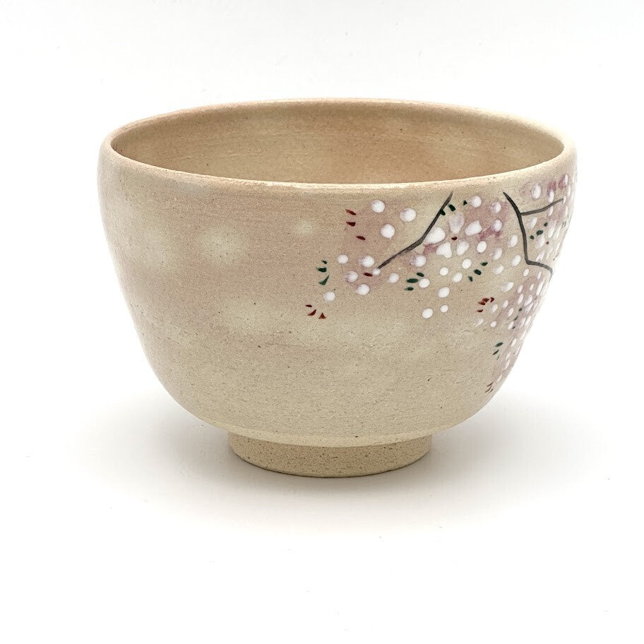 Side view of the Kyo Ware chawan highlighting hand-painted pink and white cherry blossoms on the softly textured beige glaze