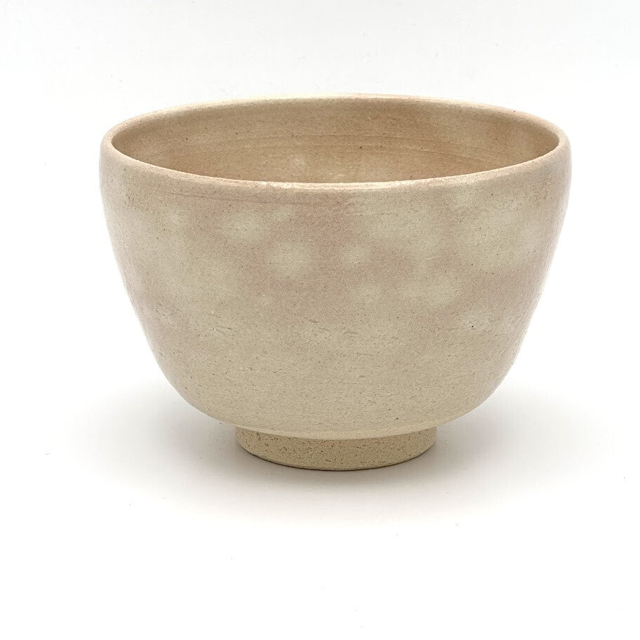 Reverse view of the Sakura Kyo Ware matcha bowl showing its rounded form and softly mottled beige glaze