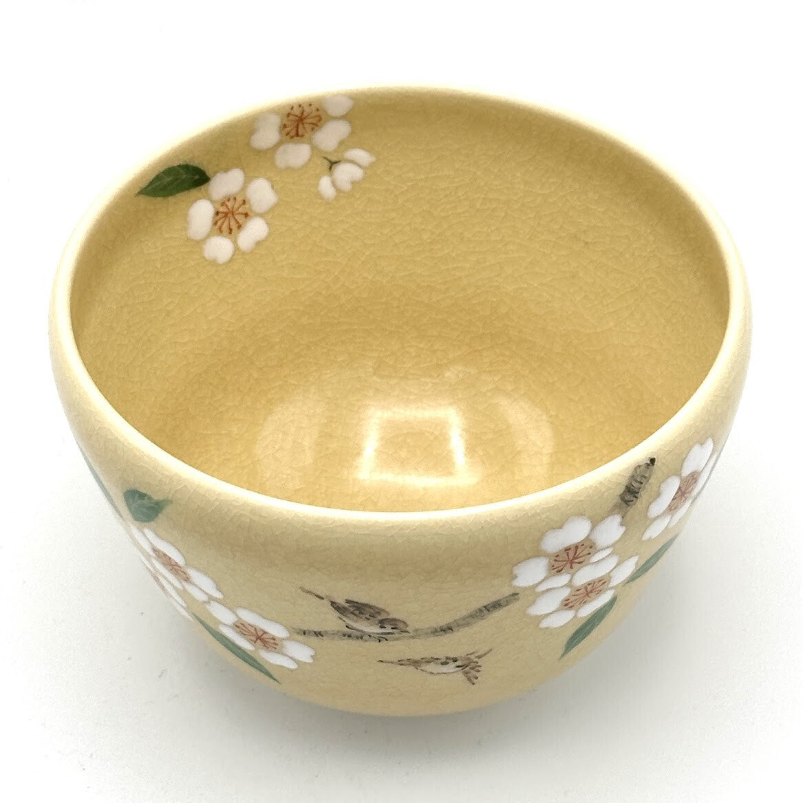 Angled top view of the sakura and songbird matcha bowl showing its warm beige interior and cherry blossoms around the rim.
