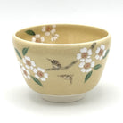 Front view of a hand-painted Kyo Ware matcha bowl decorated with cherry blossoms and two songbirds.