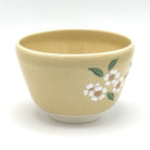 Right-side view of the Kyo Ware matcha bowl with a cherry blossom branch and a small songbird near the base.