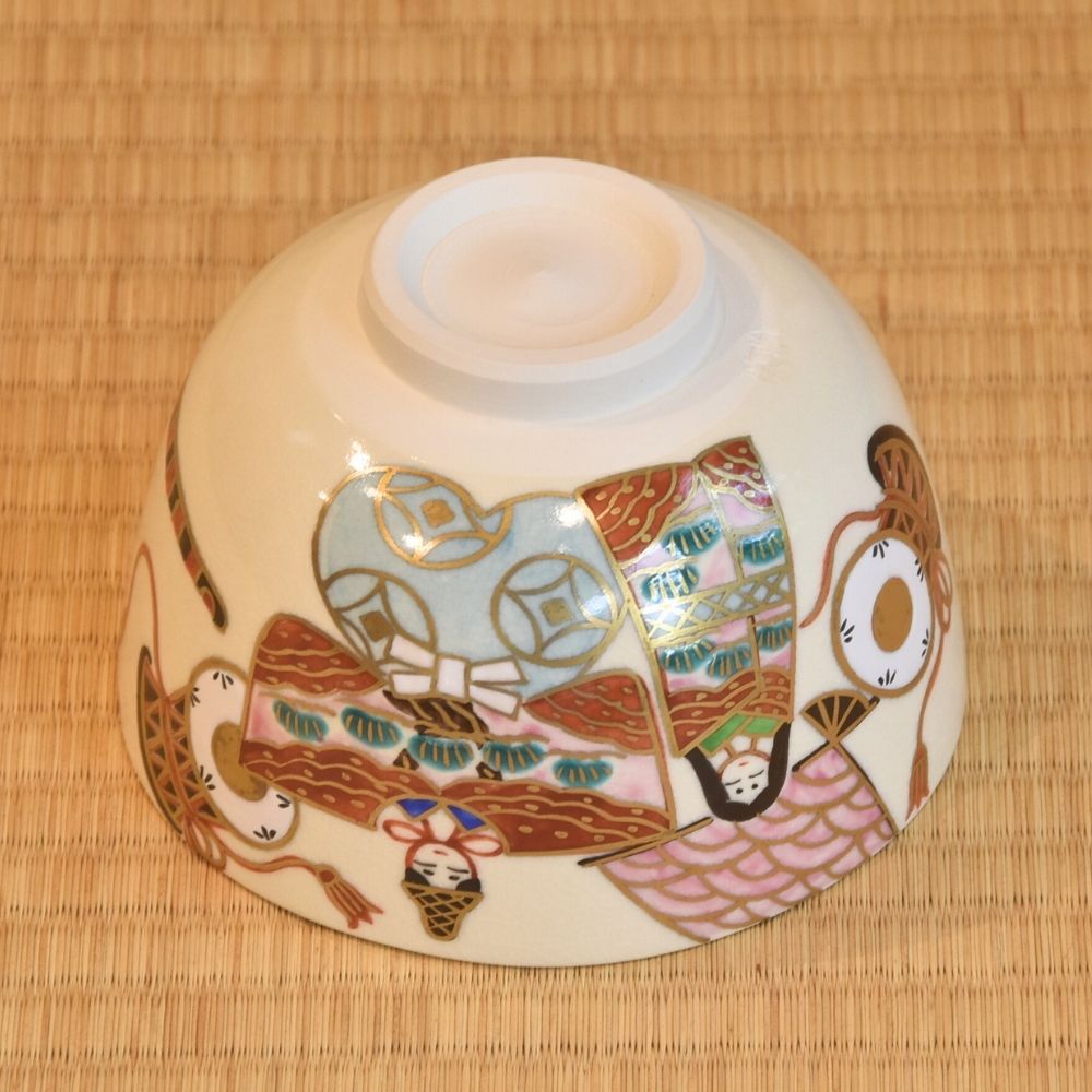 Angled underside view of the hand-painted Kyo Ware bowl showing the raised foot and colorful Hina Matsuri decoration around the exterior.