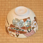 Angled underside view of the hand-painted Kyo Ware bowl showing the raised foot and colorful Hina Matsuri decoration around the exterior.