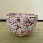 Decorative glass bowl with cherry blossom design on a woven mat